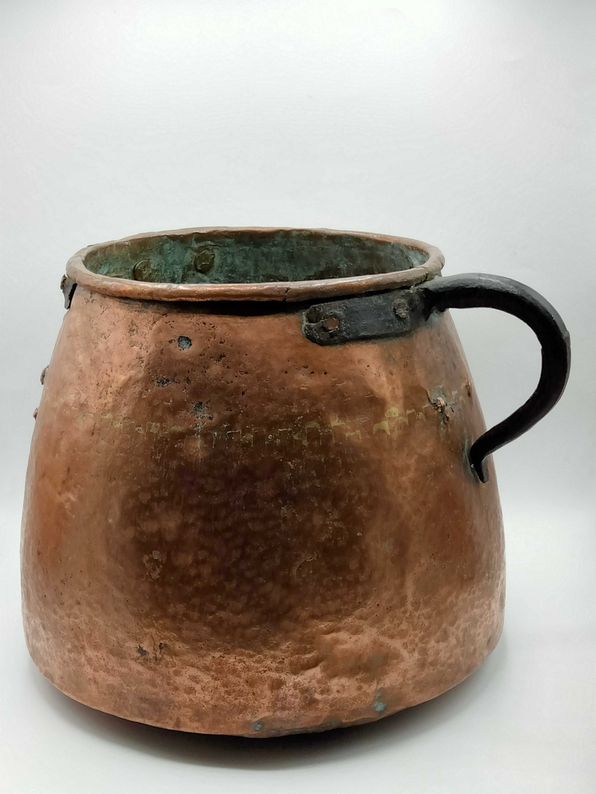 Vista lateral de olla de cobre tradicional martillada del siglo XIX, con pátina verde interior y detalles artesanales únicos para decoración de hogar.