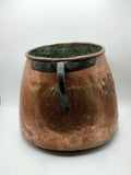 Olla antigua de cobre martillado con asa metálica, perfecta para decoración vintage en espacios de estilo colonial o rústico.