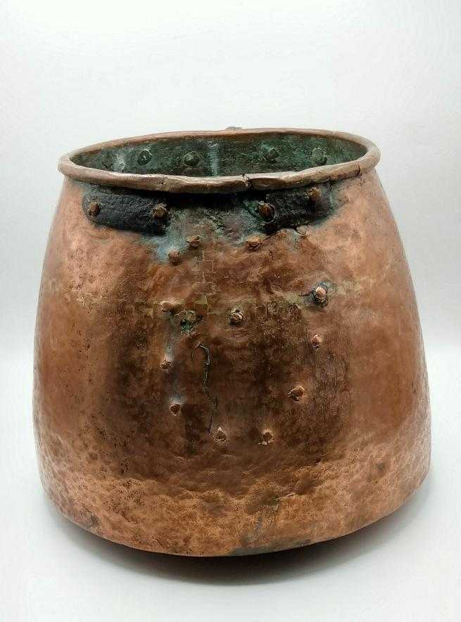 Parte trasera de olla de cobre martillada a mano, con signos de envejecimiento natural, ideal para decoración de jardín o interiores clásicos.