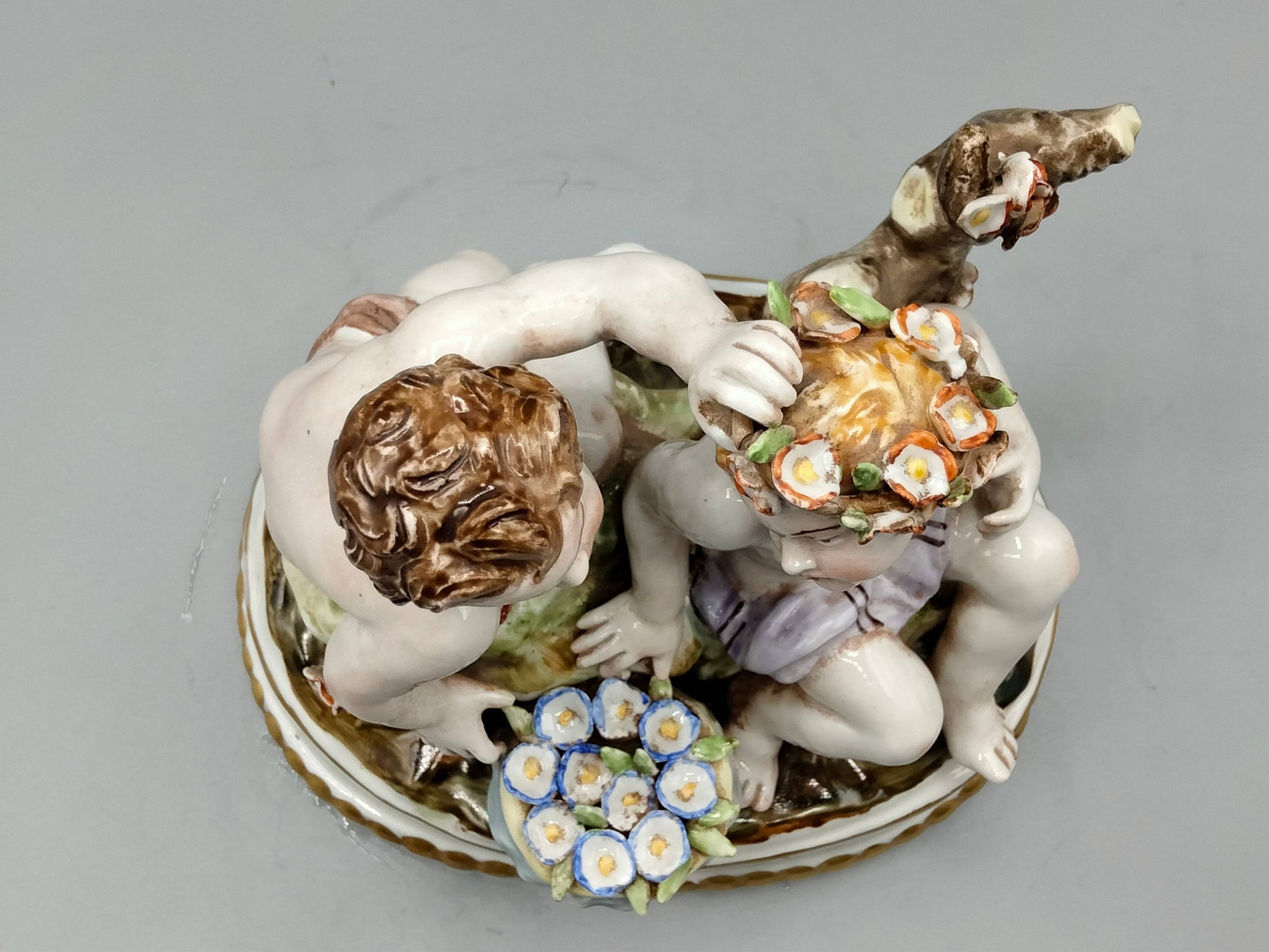Vista superior de figura de porcelana Hispania Manises, niños jugando con flores y detalles pintados a mano, ideal para coleccionistas.