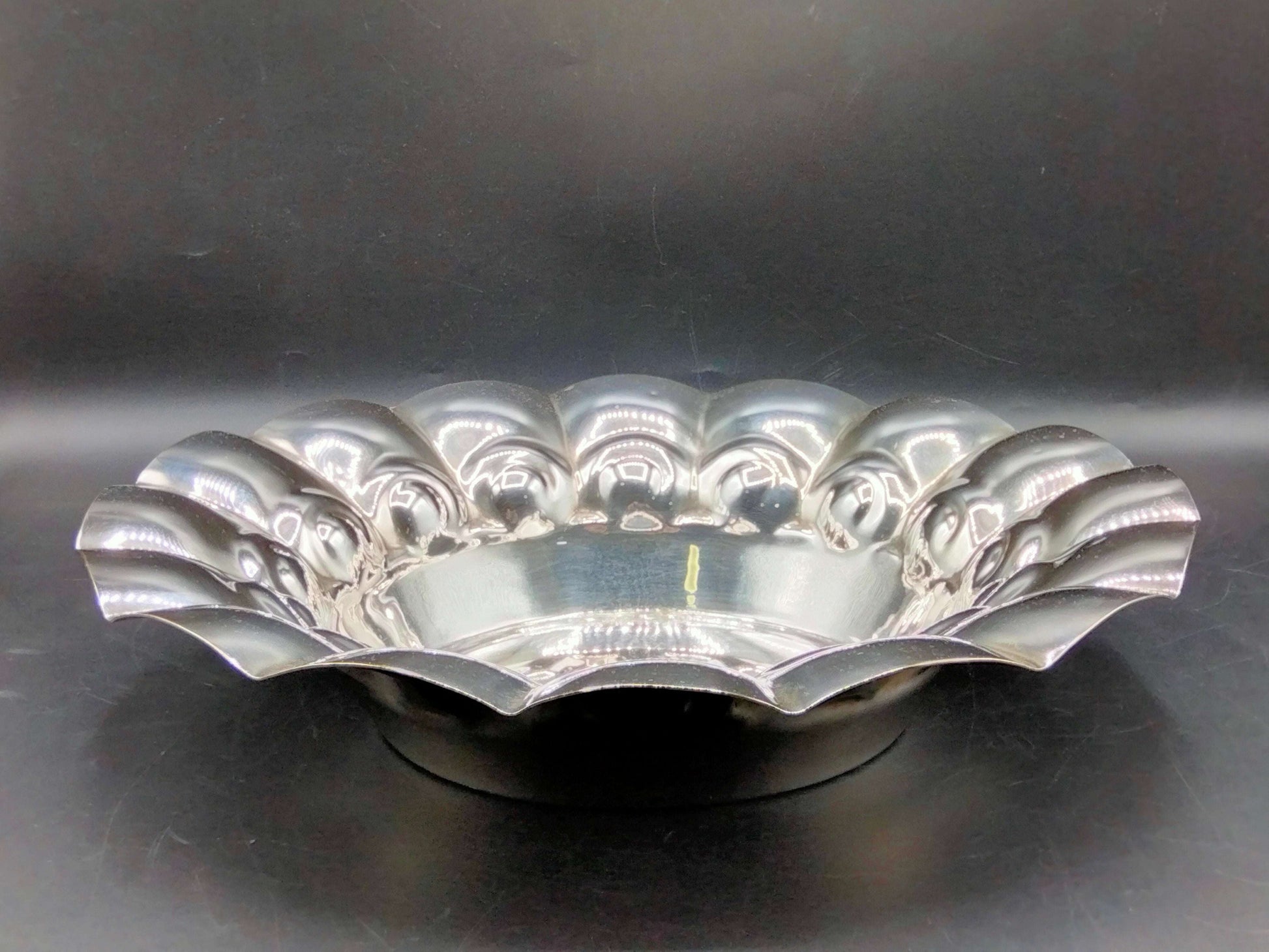 Plato de metal plateado con diseño ondulado, ideal para decoración elegante en el hogar. Versátil y funcional para estilos clásicos o vintage.