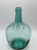 Damajuana 5 litros de cristal soplado verde con acabado artesanal, ideal para decoración vintage en interiores de hogar o jardín.