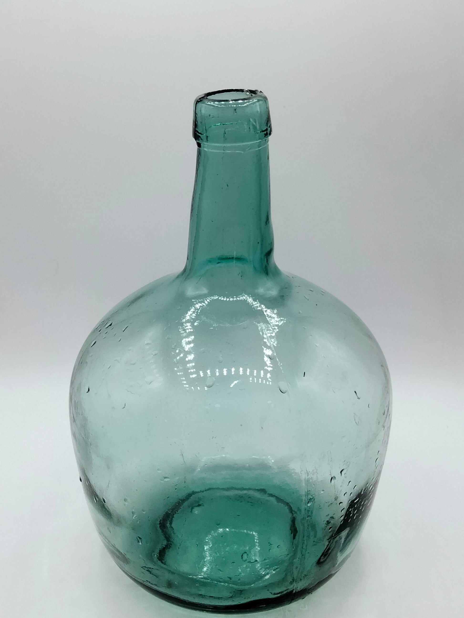 Damajuana 5 litros de cristal soplado verde con acabado artesanal, ideal para decoración vintage en interiores de hogar o jardín.