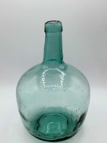 Damajuana 5 litros de cristal soplado verde con acabado artesanal, ideal para decoración vintage en interiores de hogar o jardín.