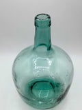 Botella damajuana decorativa de 5 litros en cristal soplado verde, perfecta para añadir un toque rústico y elegante a cualquier espacio.