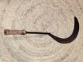 Hocino curvado con mango de madera colocado horizontalmente. Perfecto para decoración de estilo agrícola o coleccionismo.