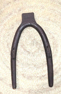 Horcate aéreo de hierro en herradura para caballerías sobre fondo de mimbre, ideal para decoración rústica en establos o casas rurales.