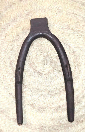 Horcate aéreo de hierro en herradura para caballerías sobre fondo de mimbre, ideal para decoración rústica en establos o casas rurales.