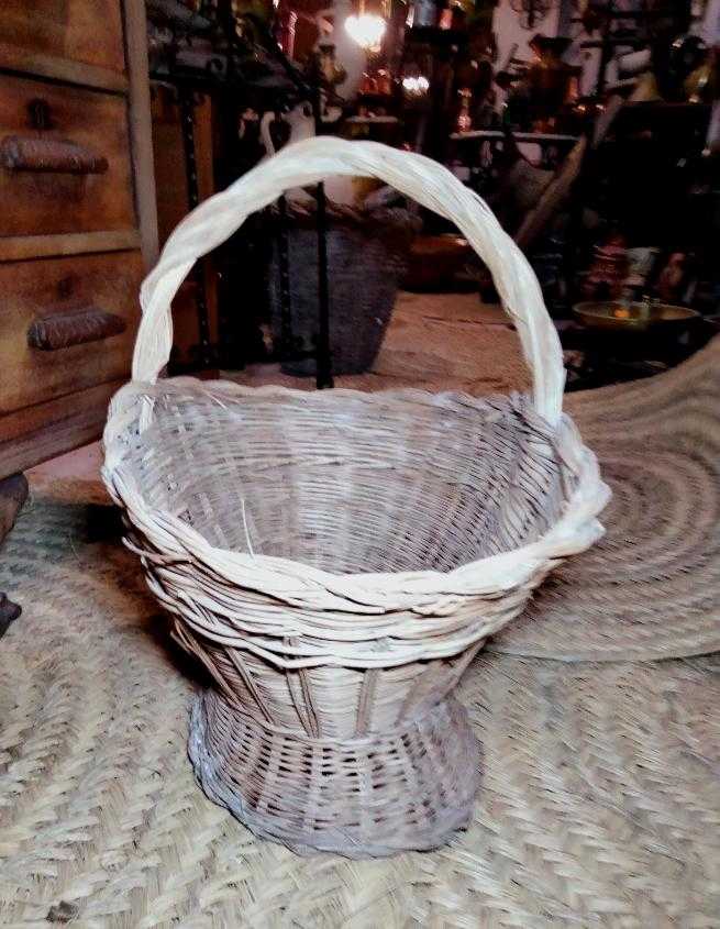 Cesteria de mimbre artesanal para flores con diseño rústico y base elevada, ideal para decoración de bodas o eventos en interiores.