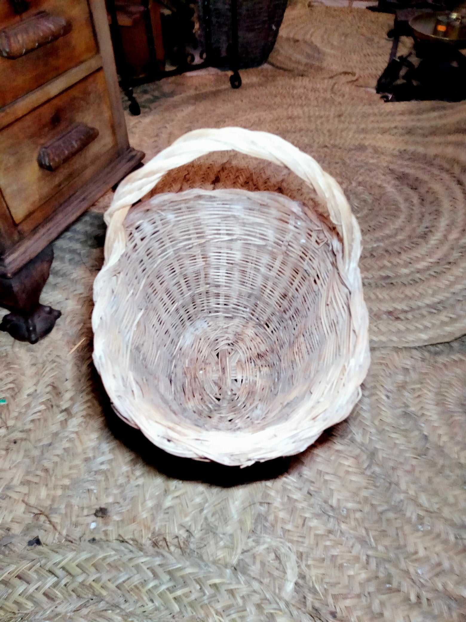 Cesteria de mimbre artesanal para flores, decorativa y versátil, colocada sobre alfombra rústica en ambiente interior de estilo vintage.