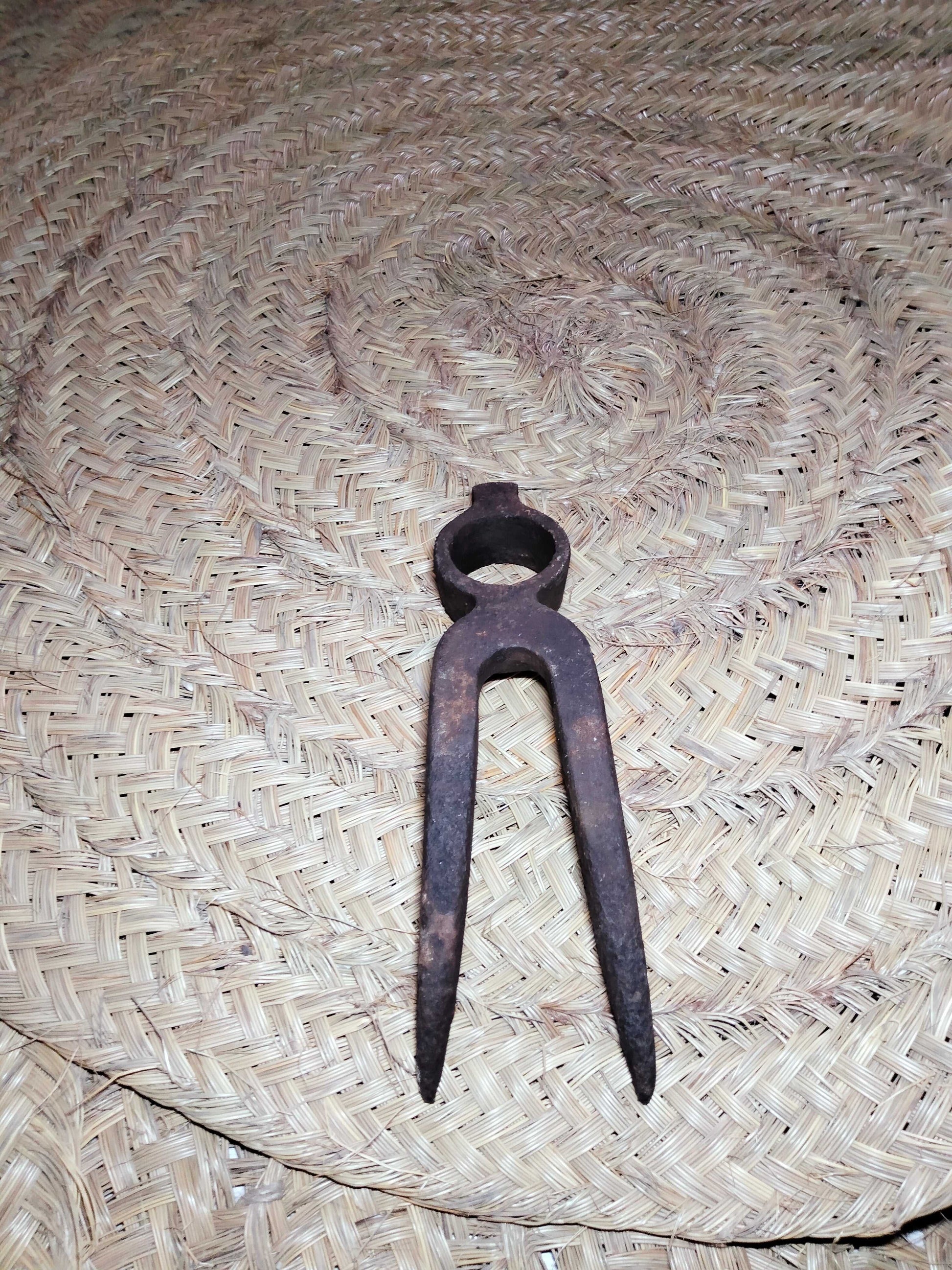 Pico antiguo para remolacha de hierro oxidado sobre fondo de mimbre, ideal como decoración rústica en hogar o jardín. Herramienta de campo histórica.