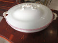 Fuente de porcelana con tapa, diseño clásico con detalles dorados y borde rosa, ideal para decoración elegante en el hogar o eventos formales.