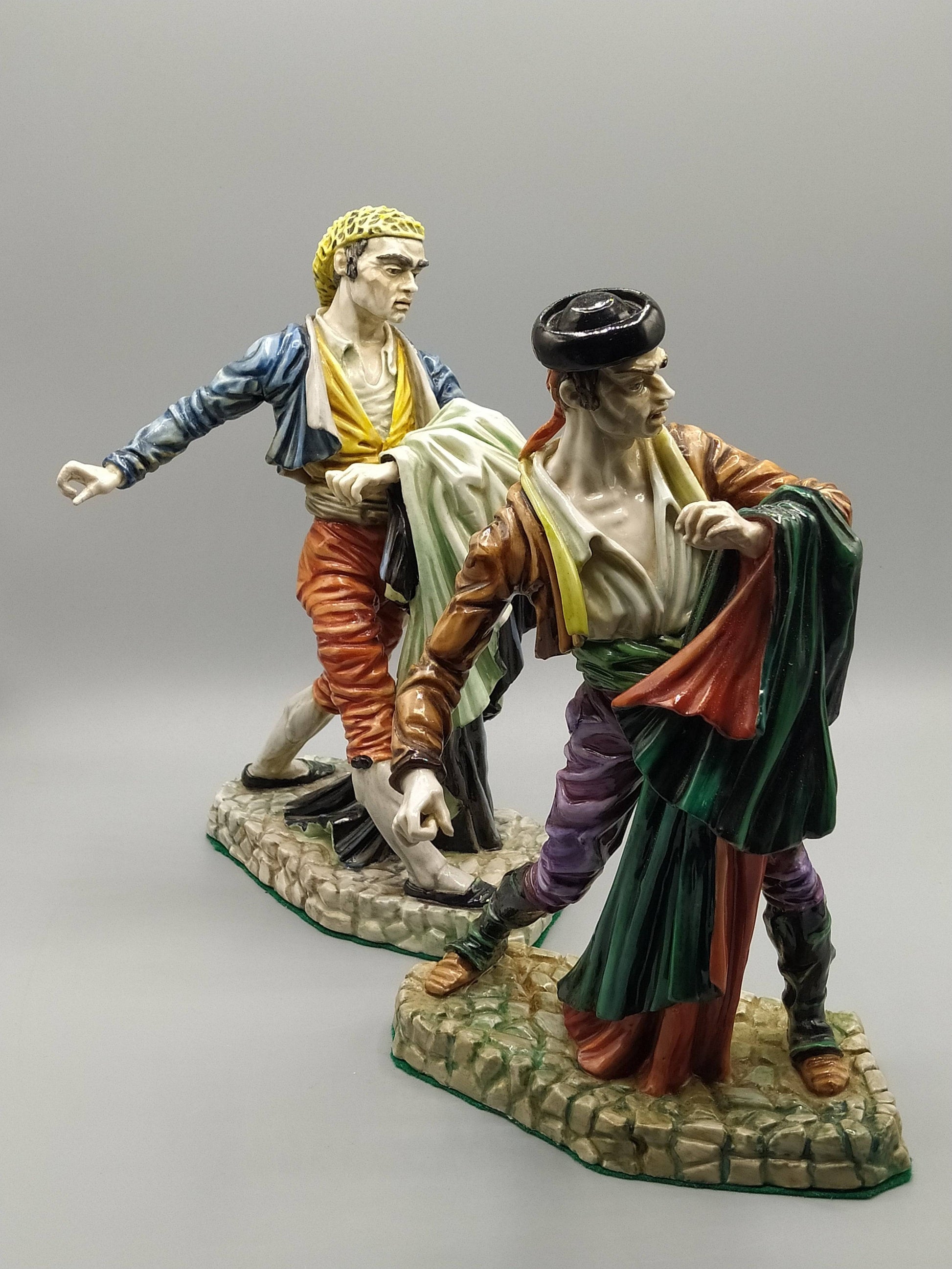 Pareja de figuras Bandoleros Algora en porcelana, representando toreros goyescos con trajes coloridos y base de piedra detallada.