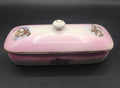 Tarro de tocador rectangular en porcelana rosa de Cartuja de Sevilla con tapa y escenas campestres pintadas. Ideal para decoración vintage.