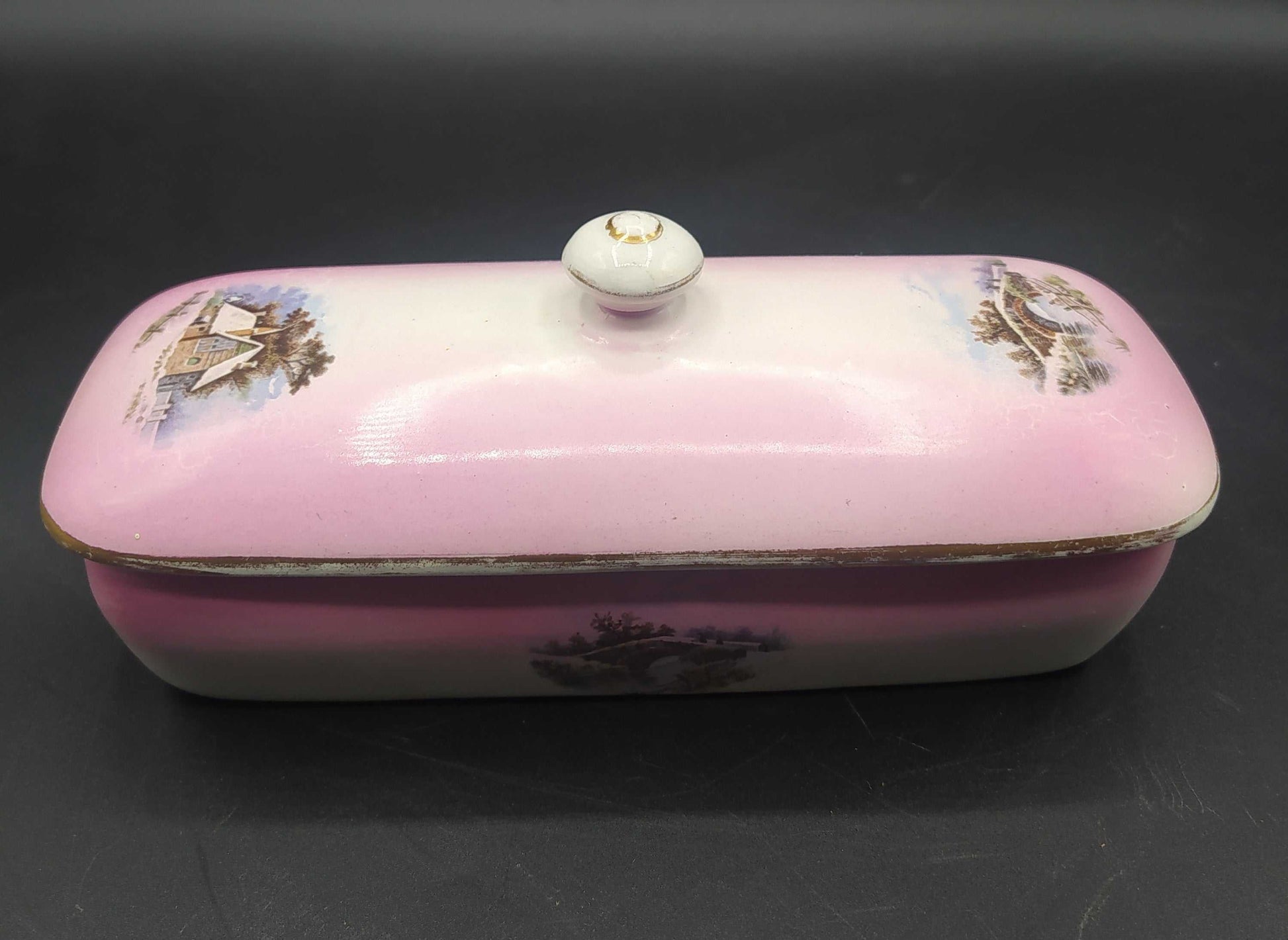Tarro de tocador rectangular en porcelana rosa de Cartuja de Sevilla con tapa y escenas campestres pintadas. Ideal para decoración vintage.