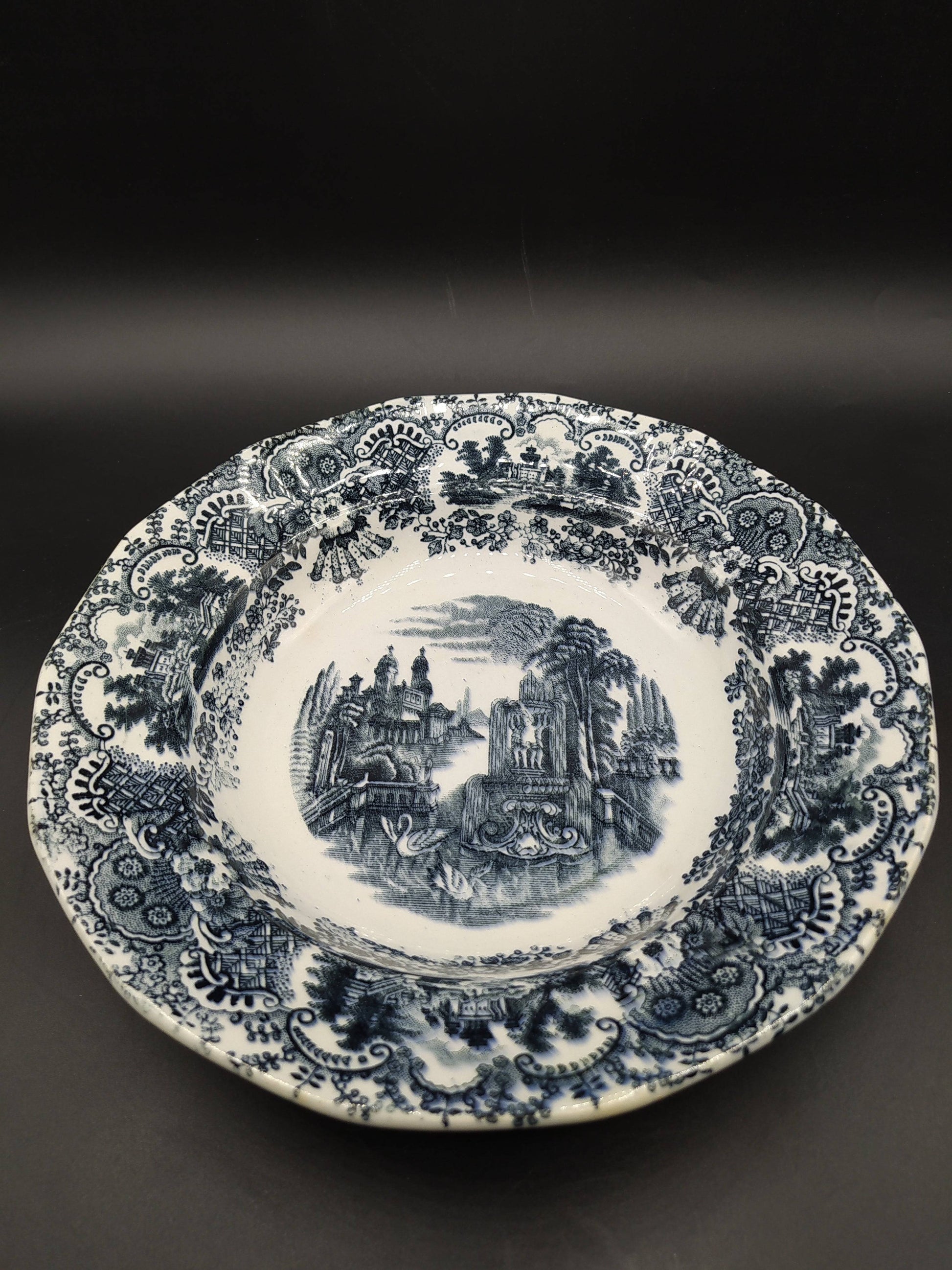 Plato hondo de porcelana La Cartuja, modelo vistas, siglo XIX, con decoración en negro de paisajes clásicos y borde ornamentado. Ideal para decoración vintage.