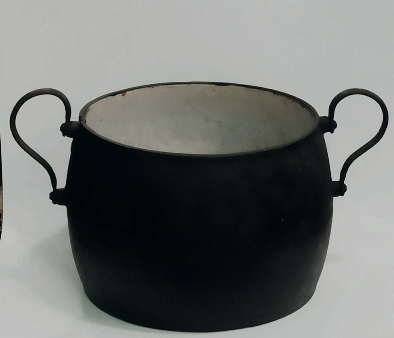 Olla de hierro antigua esmaltada con asas curvas, ideal para decoración vintage en cocinas rústicas o junto a chimeneas.