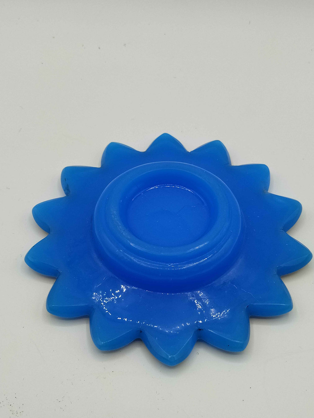 Plato de opalina azul con decorado dorado en forma de flor, ideal para decoración elegante en el hogar. Calidad premium, 14 cm de diámetro.