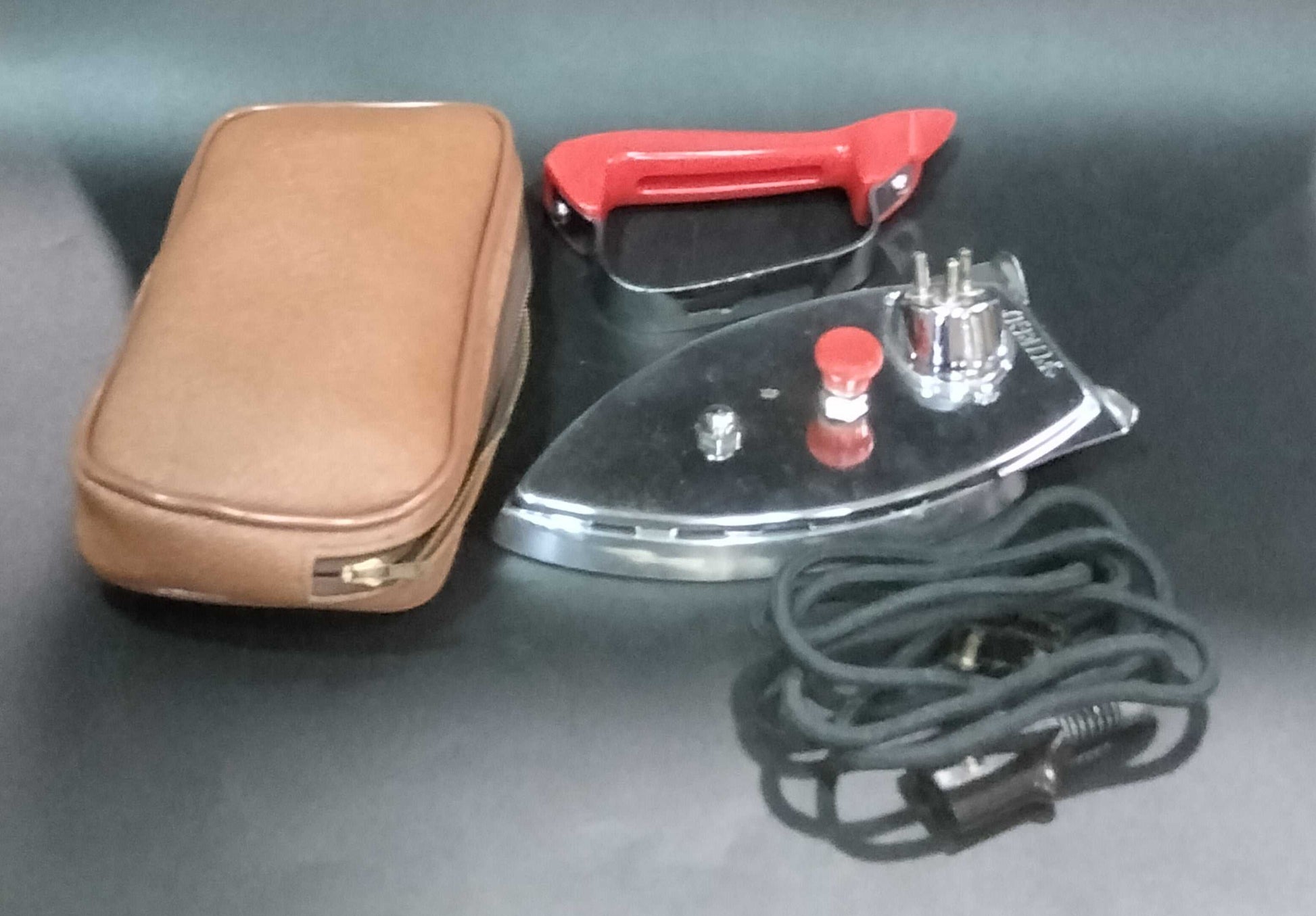 Plancha Eléctrica de Viaje Fuego desmontada con mango rojo, cable y estuche. Diseño nostálgico perfecto para decoración de hogar y colección.