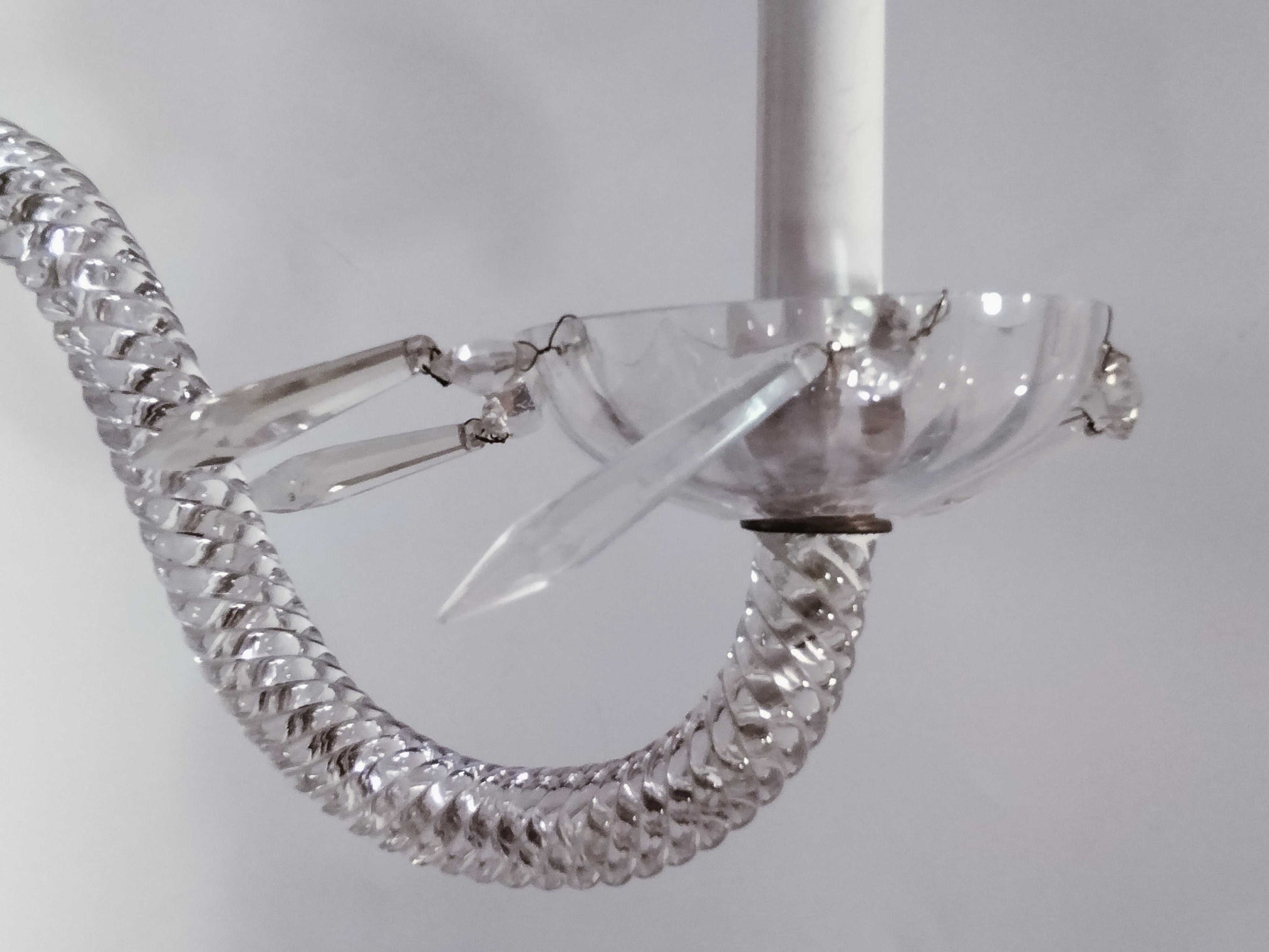 Detalle de antigua pareja de apliques de cristal de roca y metal electrificados con brazo curvo y colgantes decorativos. Ideal para iluminación de lujo.