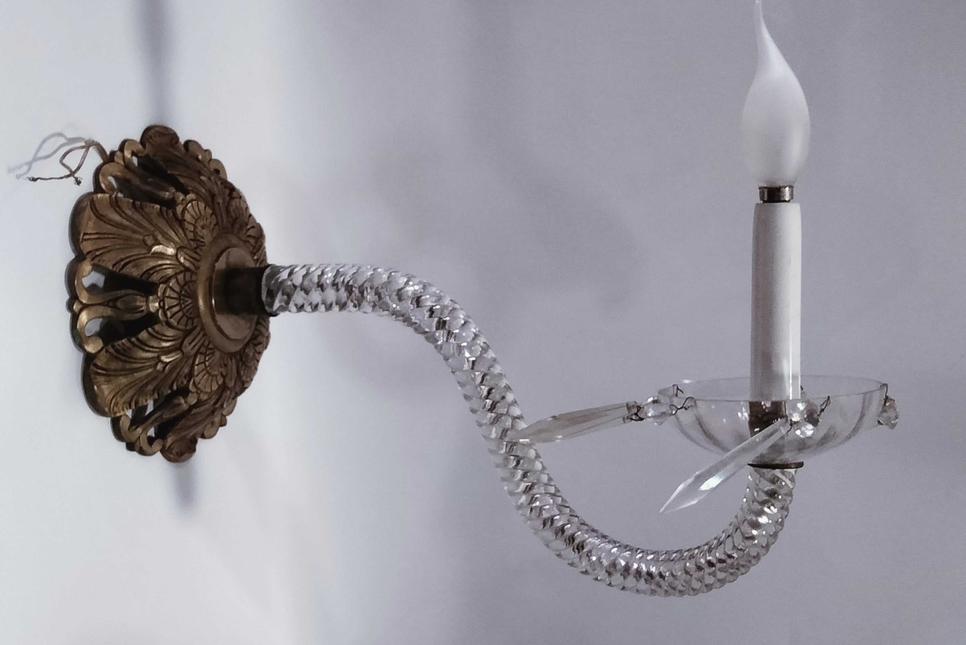 Antigua pareja de apliques de cristal de roca y metal electrificados con brazo curvo y detalles colgantes, ideal para decoración de lujo en pared.