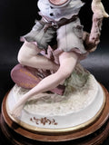 Detalle de la base y piernas de la figura de porcelana Carlos del niño músico, con acabado fino y metopa de madera decorativa.