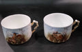 Par de tazas de porcelana Limoges del Juego de Café Tú y Yo, con asas doradas y paisajes pintados a mano, ideales para decoración o coleccionismo.