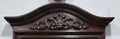 Detalle superior de espejo de consola en caoba con tallado ornamental clásico. Elegancia vintage ideal para decoración de interiores.