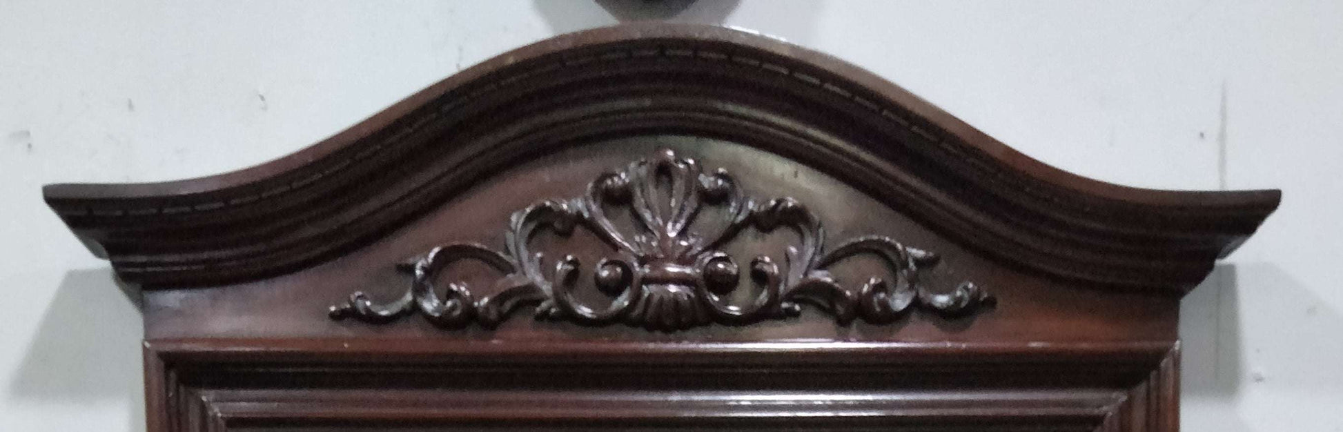 Detalle superior de espejo de consola en caoba con tallado ornamental clásico. Elegancia vintage ideal para decoración de interiores.