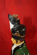 Figura de porcelana Iris Mist con forma de soldado de caballería, detalle del sombrero con tapón de corcho, fondo rojo.