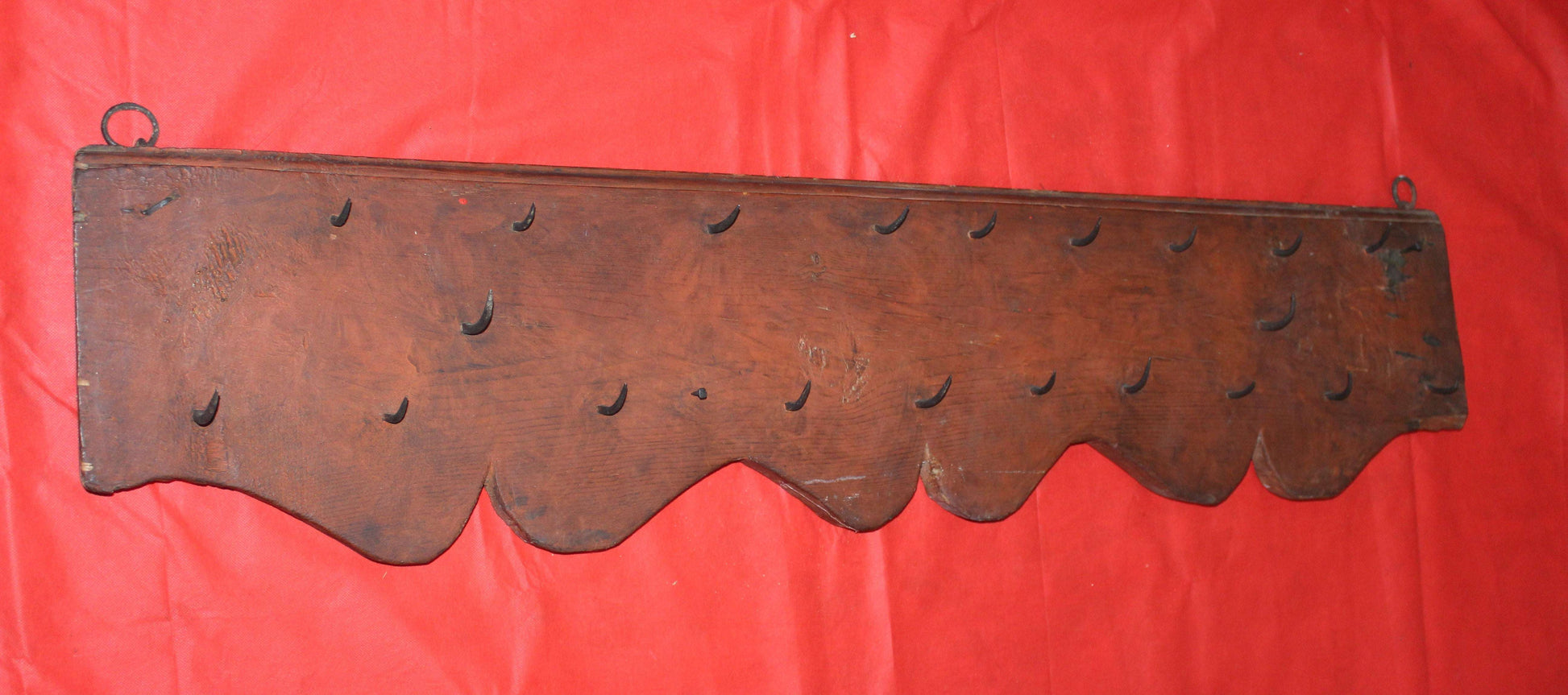 Percha antigua de matanzas con clavos de fragua, estilo rústico, hecha de madera oscura con ganchos forjados a mano. Ideal para decoración vintage en cocinas o salones de estilo rural.