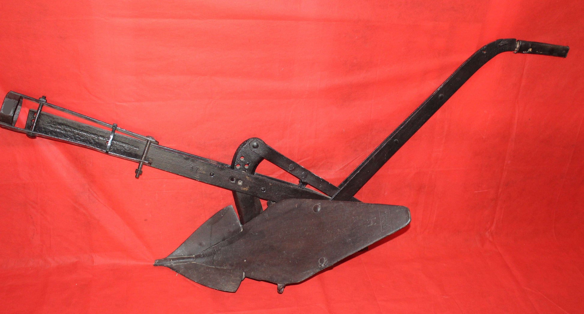 Antiguo arado de vertedera de tracción animal en hierro forjado, pieza decorativa rústica ideal para jardín o interiores vintage.