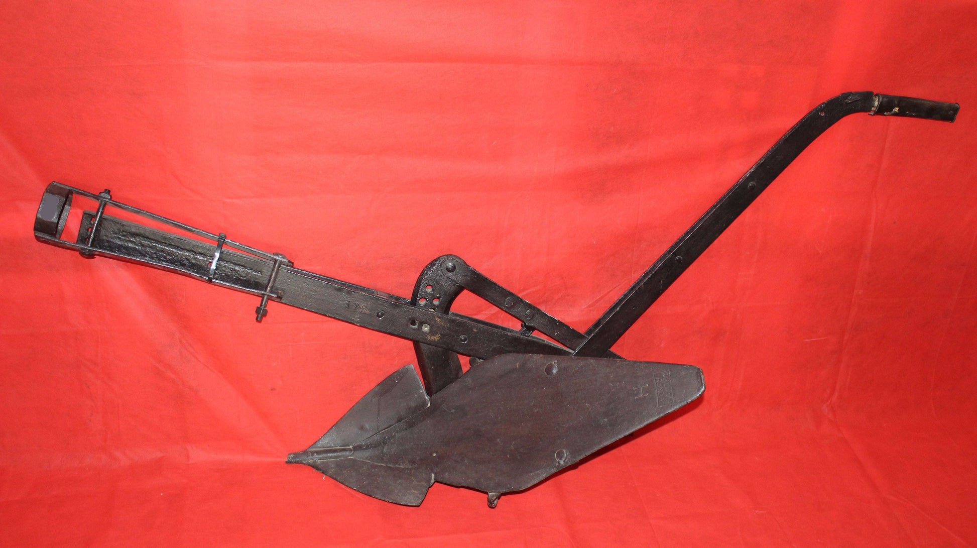 Antiguo arado de vertedera de tracción animal en hierro forjado, pieza decorativa rústica ideal para jardín o interiores vintage.
