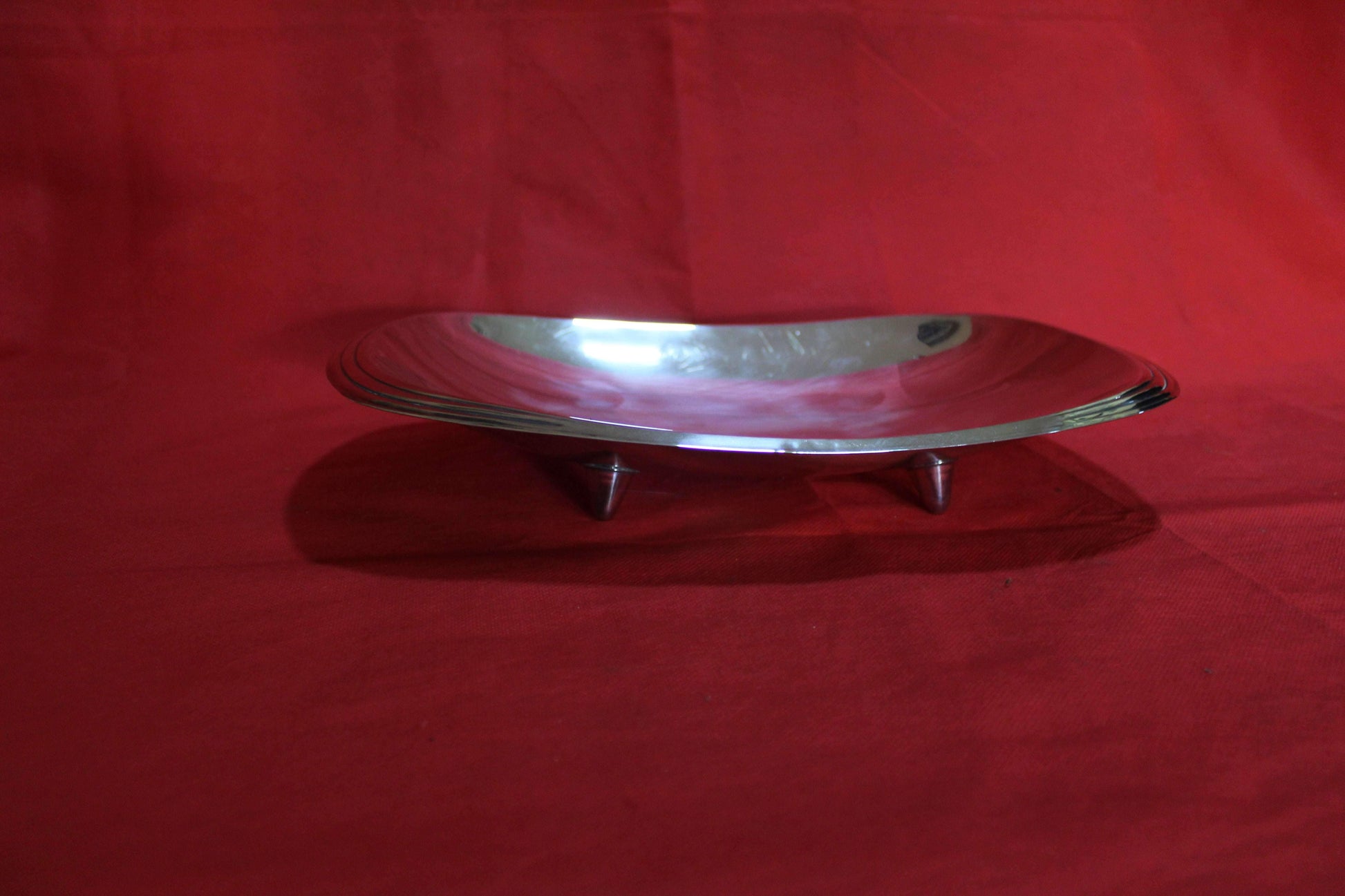 Bandeja con patas de metal plateado de alta calidad sobre fondo rojo, ideal para decoración elegante en el hogar o eventos especiales.